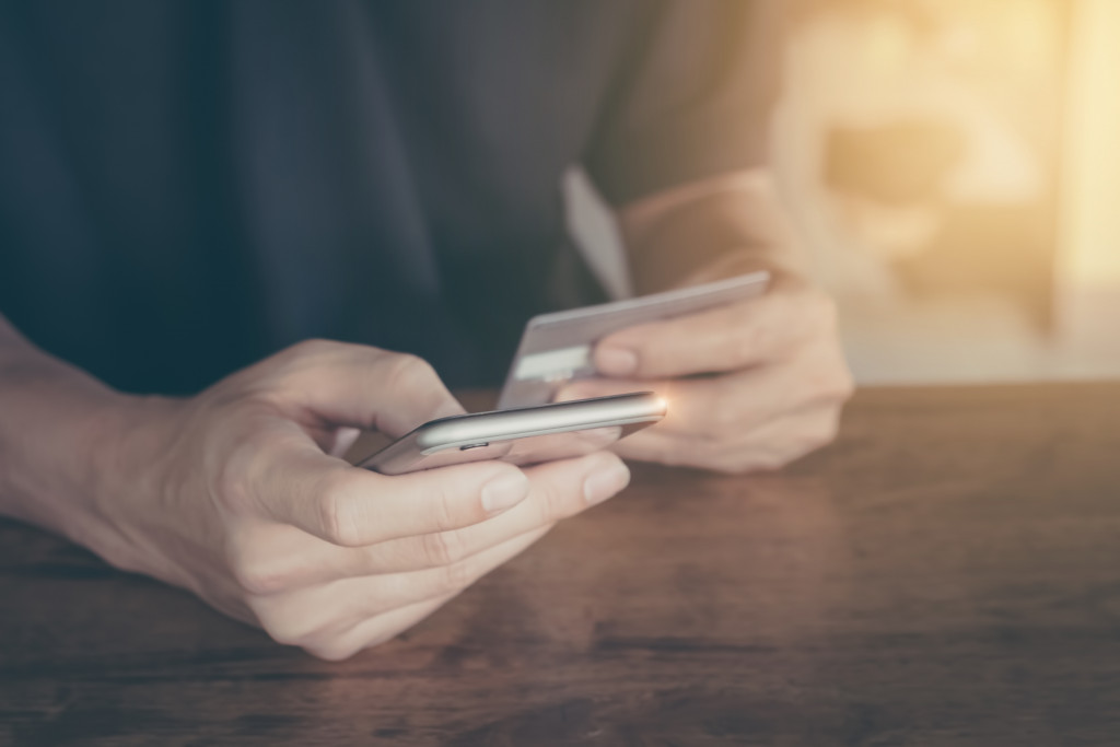 man holding card and phone