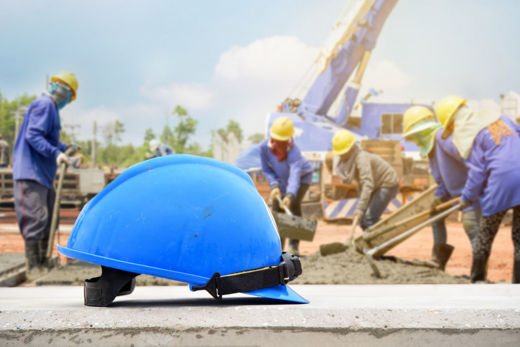 A blue construction helmet with workers in the background