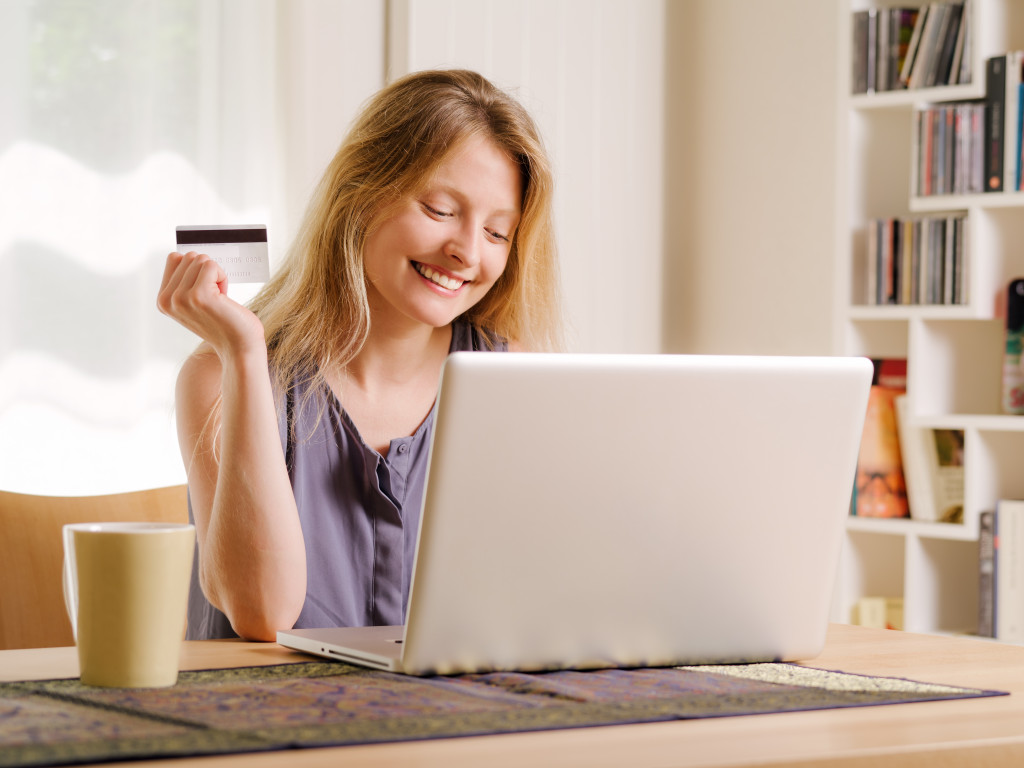 a woman holding a credit card while browsing the laptop