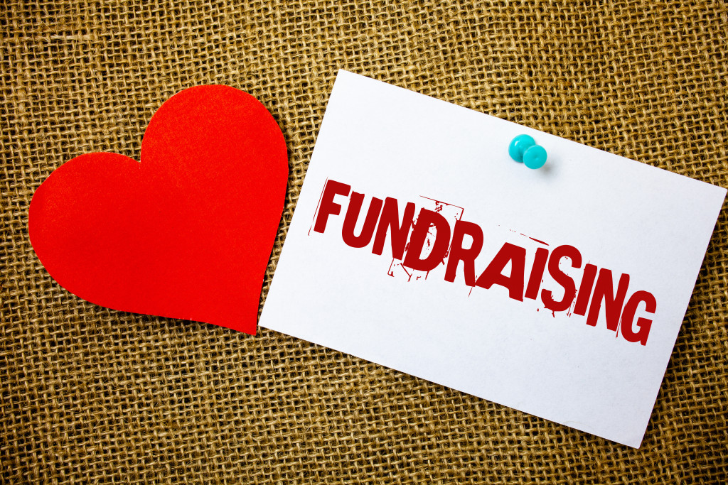Visual representation of fundraising with the words written on white paper placed beside a heart cutout.