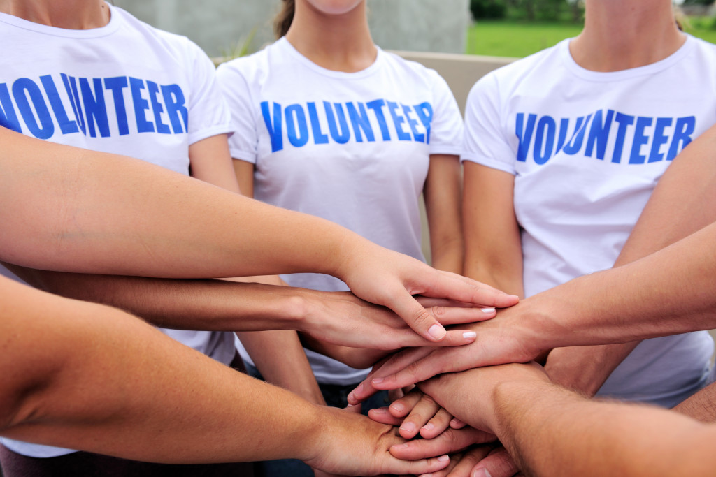 A group of people wearing Volunteer shirts putting their hands over each other