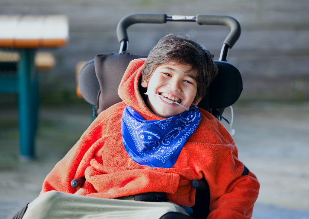 Handsome and happy eight year old boy smiling in wheelchair outdoors