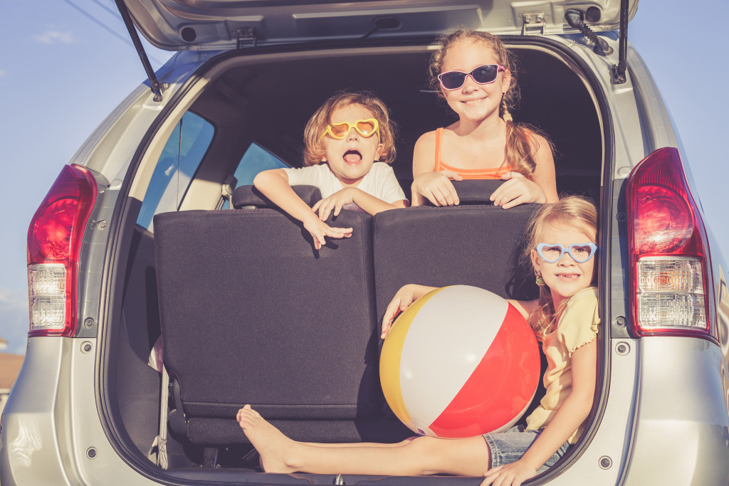 Three kids happily sitting in car and prepare for a road trip 