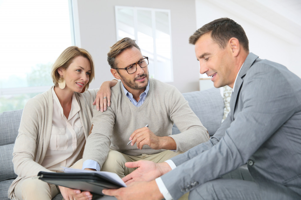 Businessman speaks to clients while showing them data on paper 