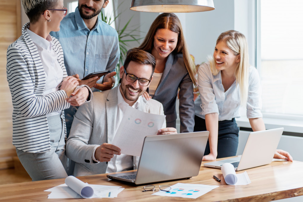 Employees checking sales on a printed form with a laptop in front of them.