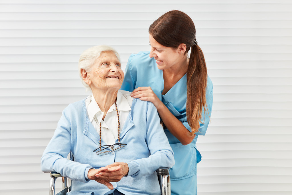 A caregiver talking with a senior lady in wheelchair