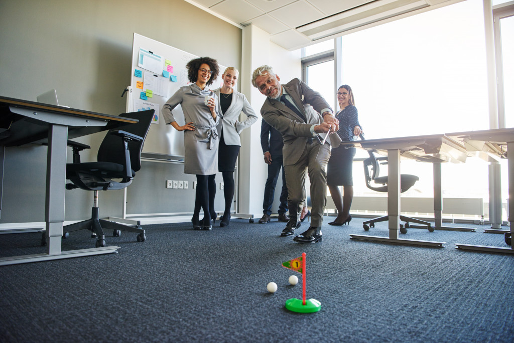 Business professionals playing mini golf in the office