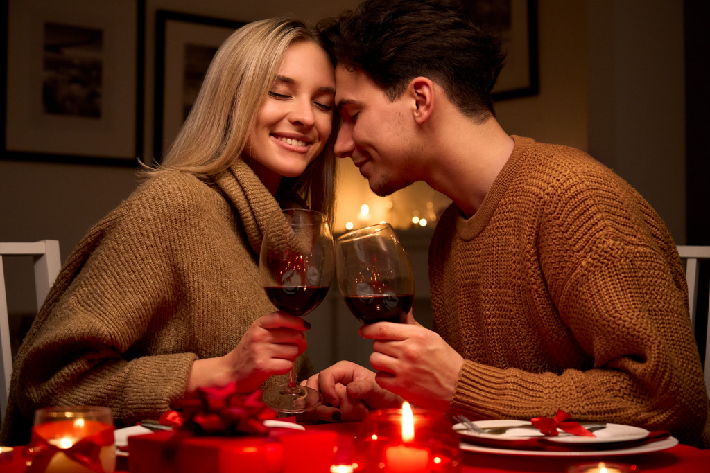 Happy young couple in love clinking glasses drinking wine having romantic dinner 