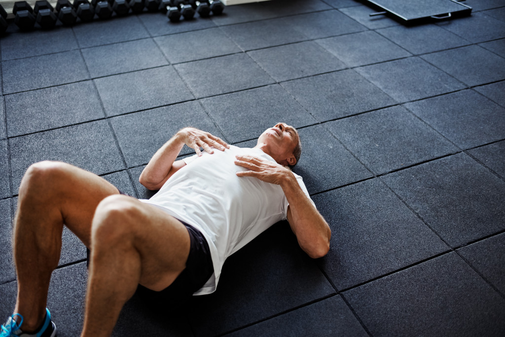 A tired man lying on the floor after working out at the gym