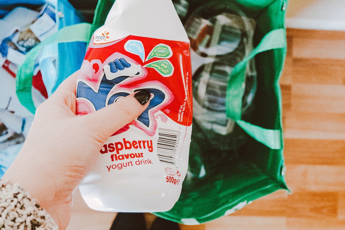 Person Holding Red and White Disposable Bottle