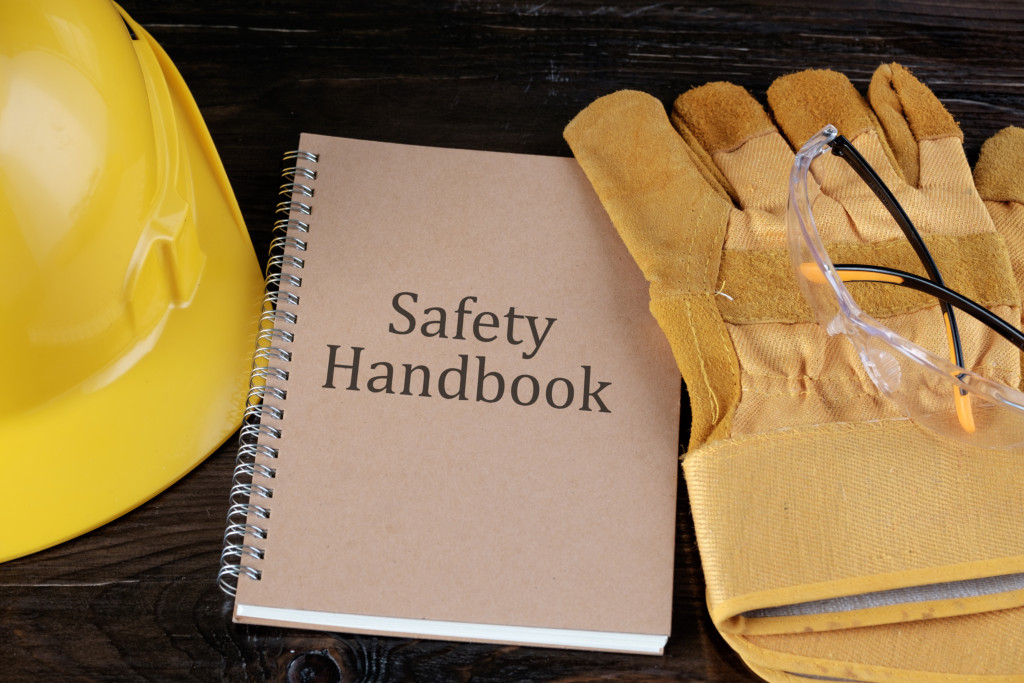 a safety handbook surrounded by a hard hat, gloves, and a safety goggles
