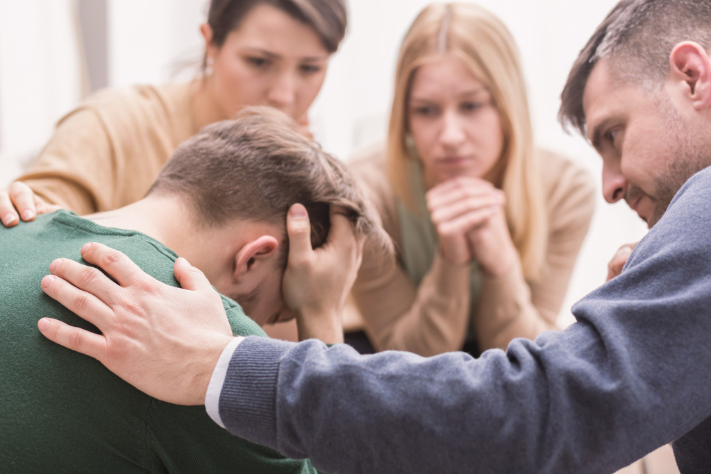 A man being comforted during a group therapy session