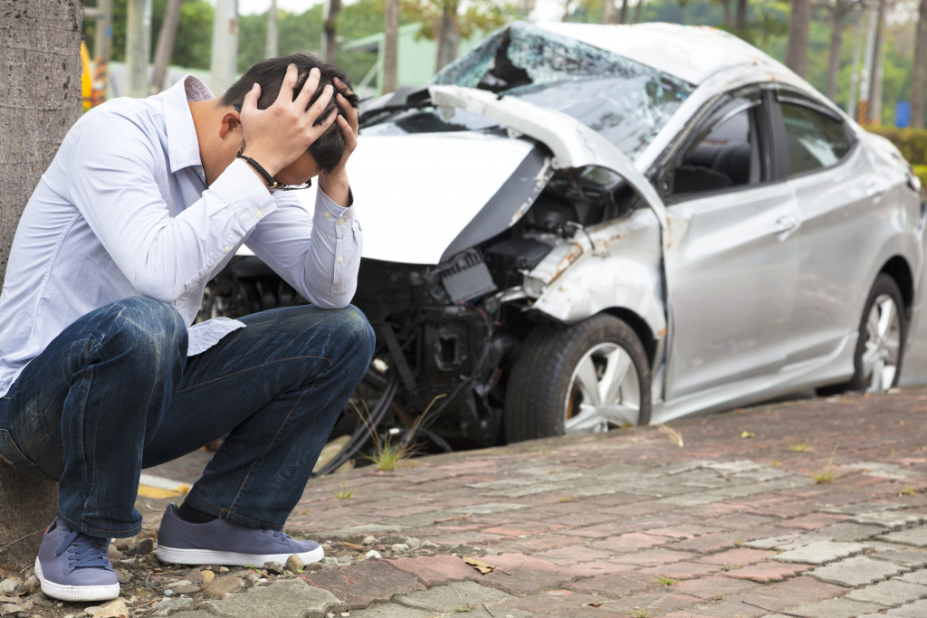 A worried man near a totally wrecked car