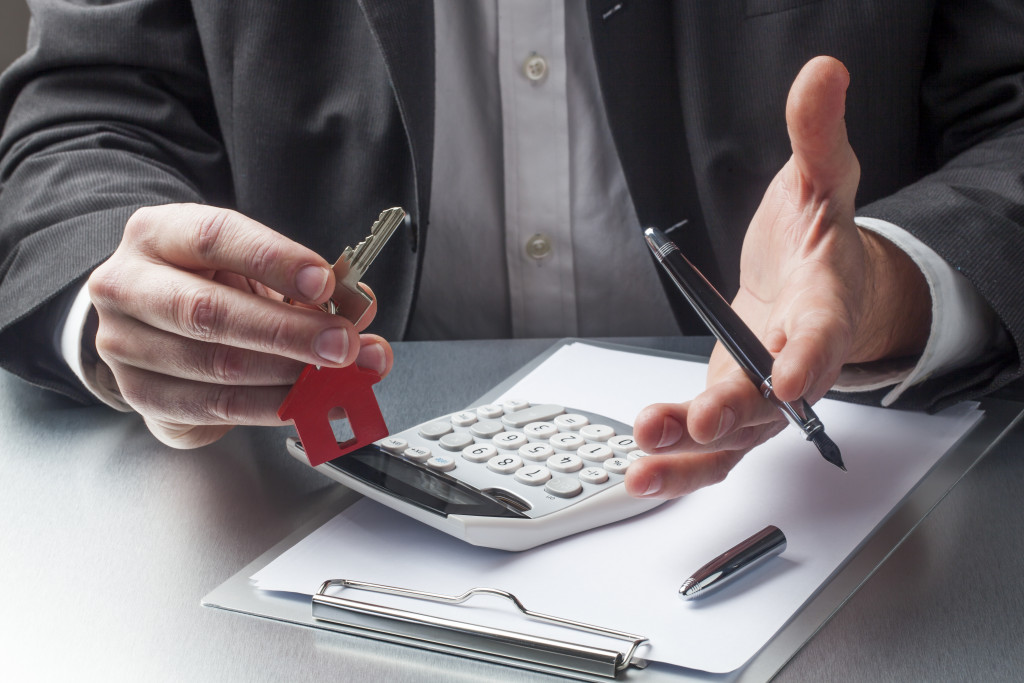 a man holding keys and calculator with document