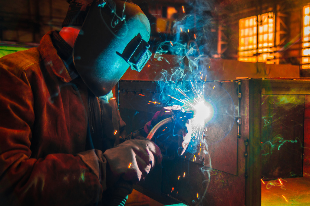 A welder with a mask working in a dark shop