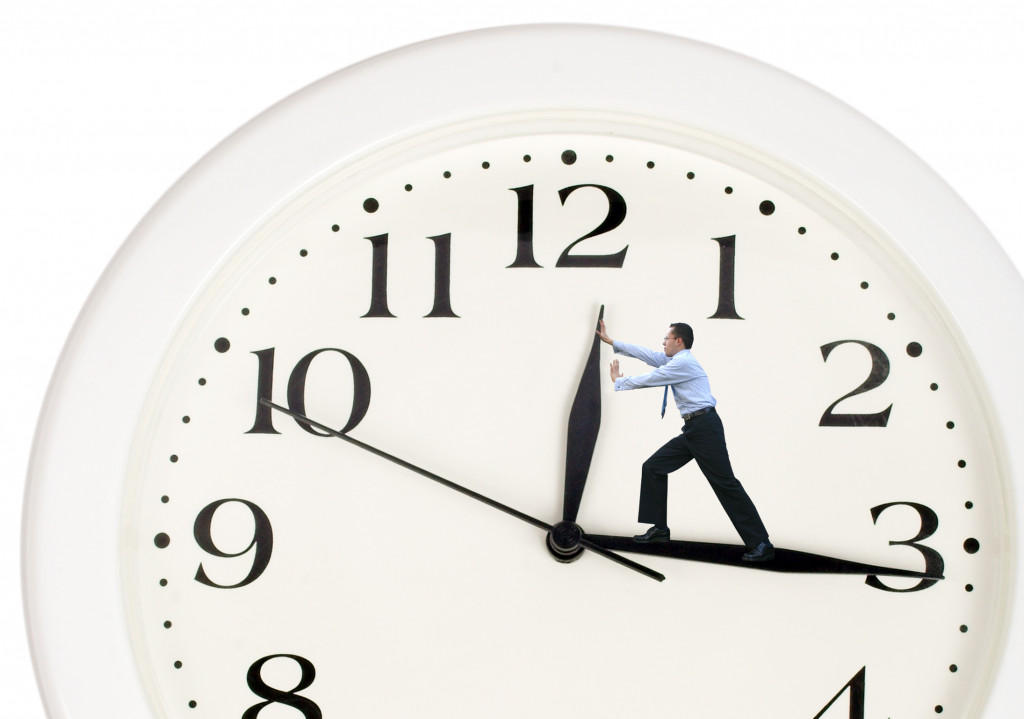 businessman pushing the hands of a white clock