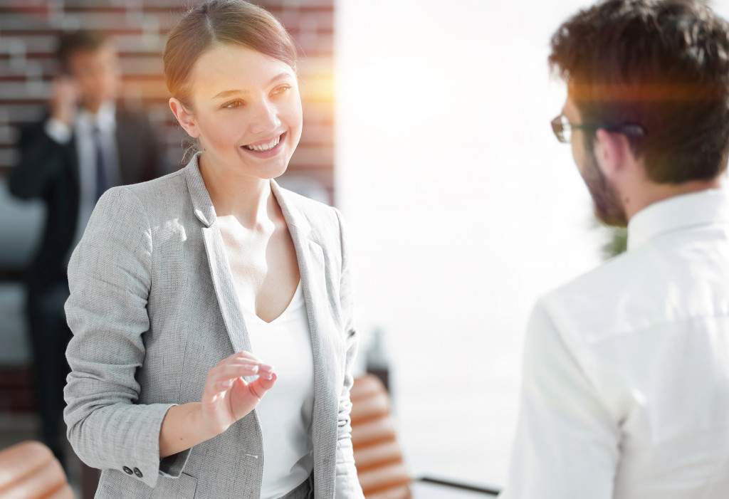 Young woman taking charge of a project while discussing it with a male colleague.