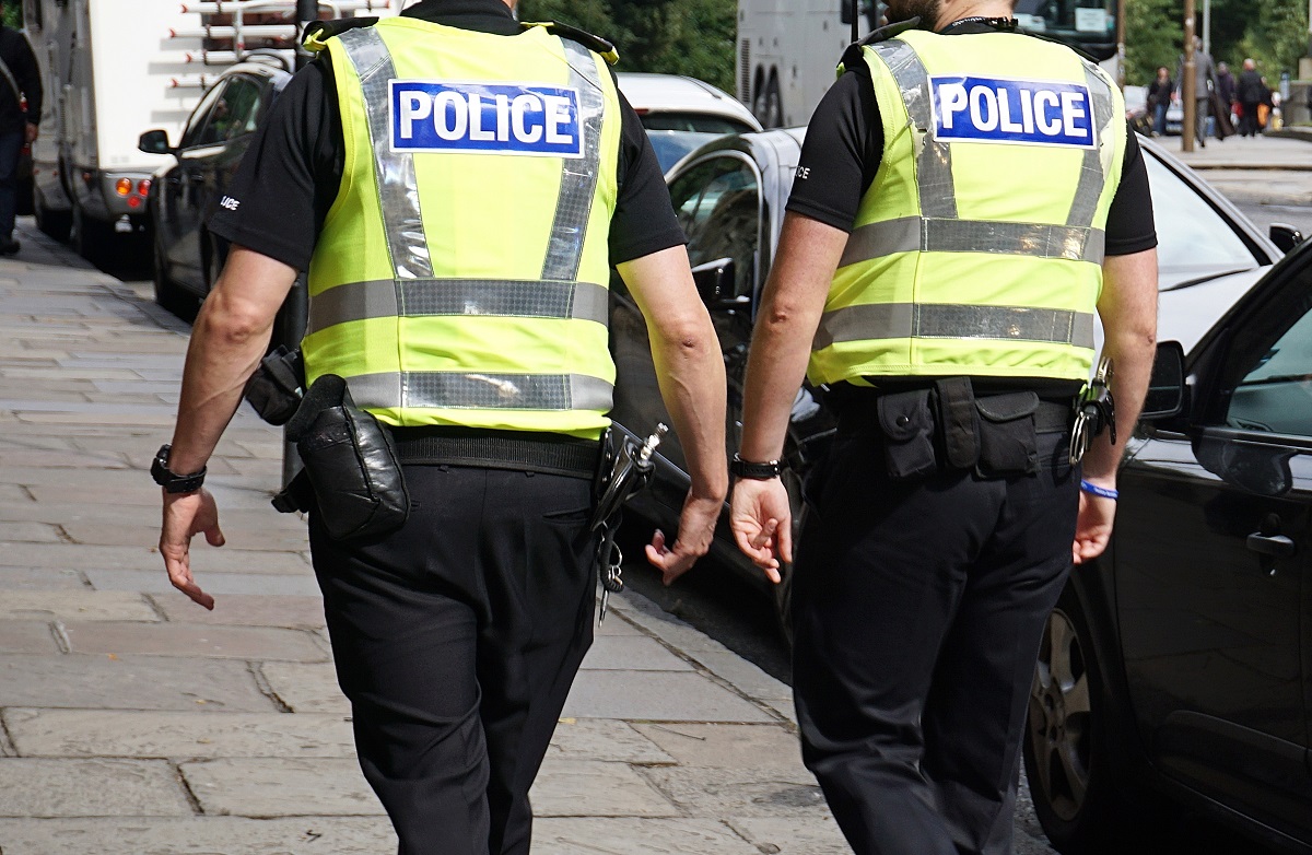 Two police in uniforms walking on the street