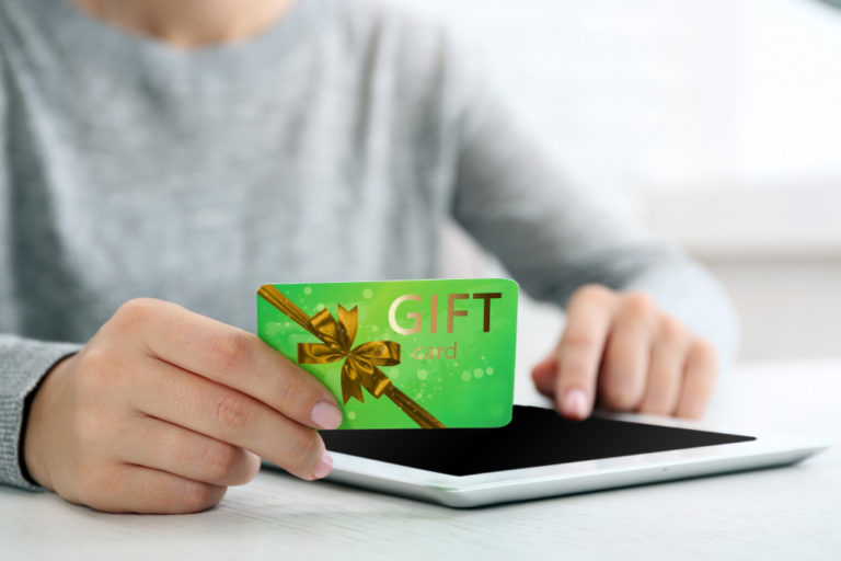 man holding gift card over tablet