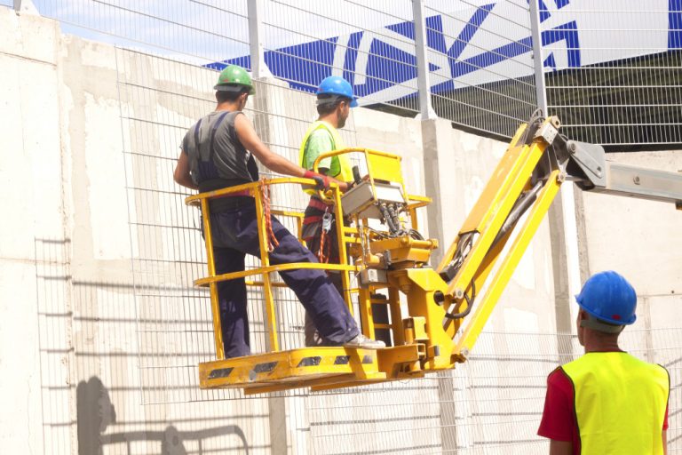 Hydraulic mobile construction platform elevated towards a blue sky with construction workers