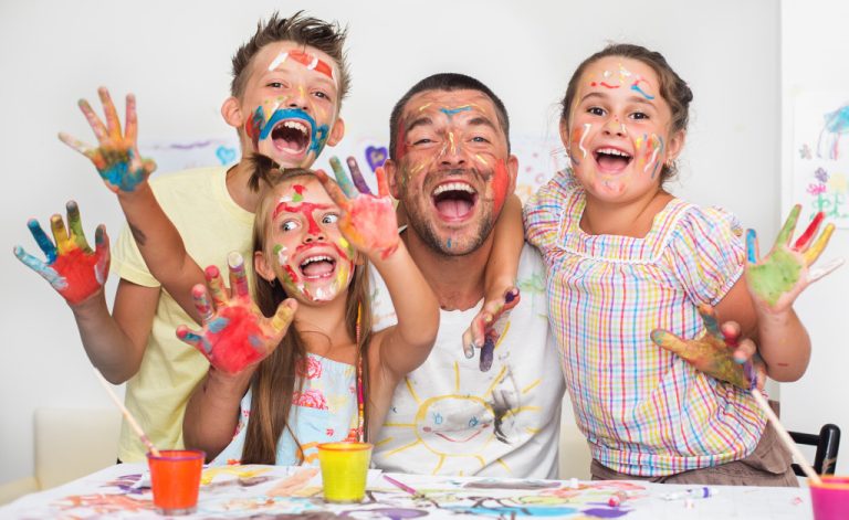kids playing with paint happily with a male adult in class
