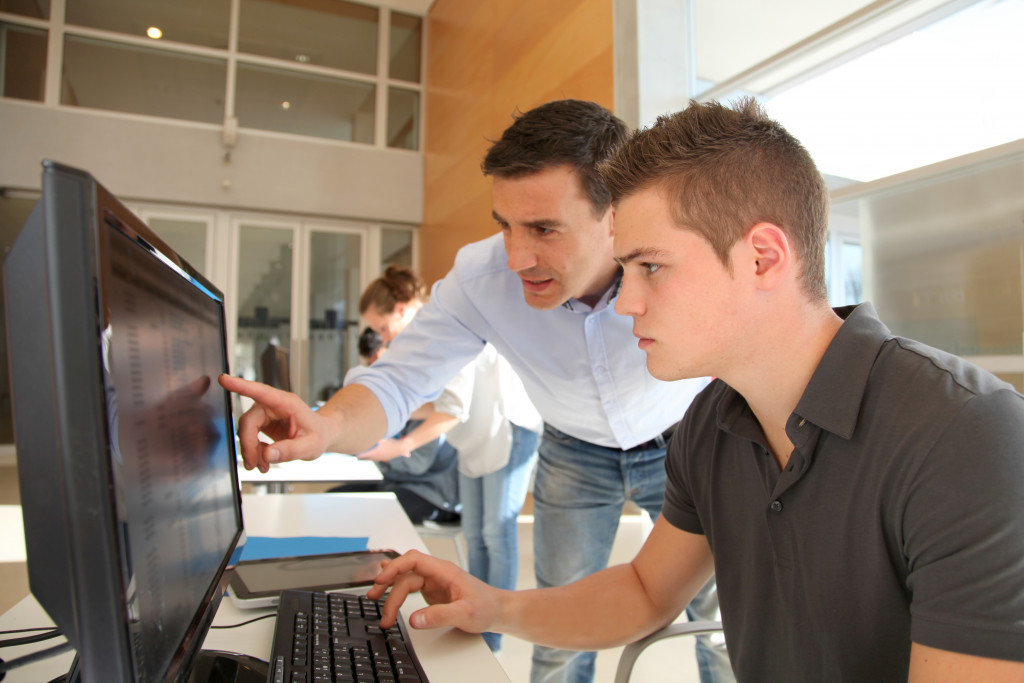 a teen student working on a computer with mentor