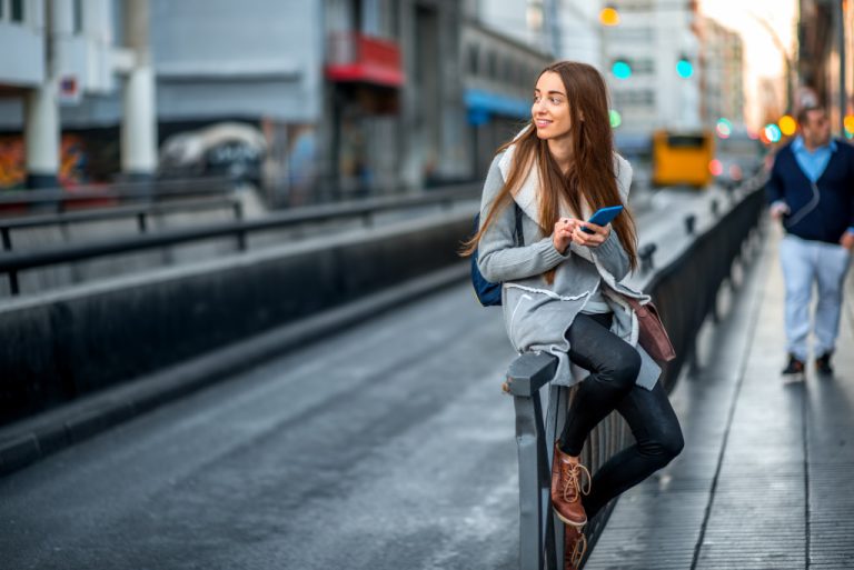 young woman sitting on a rail in the city
