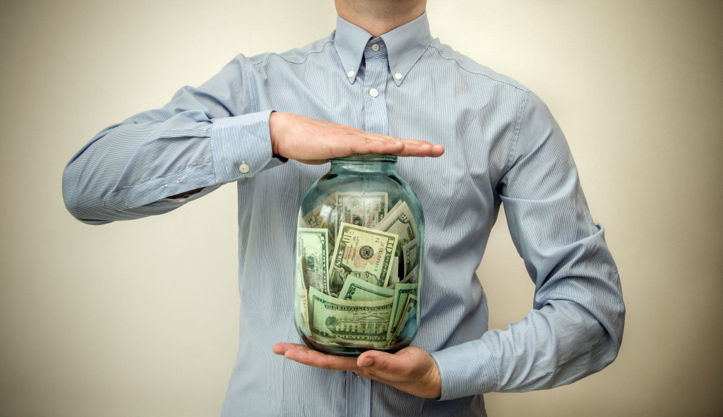 man holding jar full of money