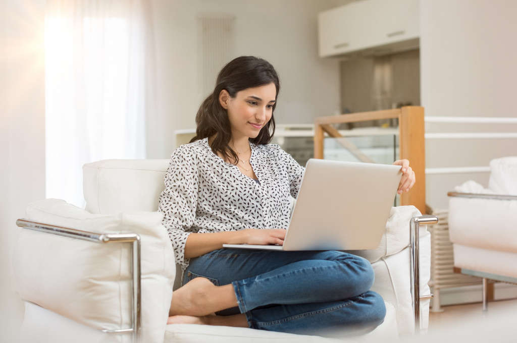 woman sitting on the couch researching on her laptop