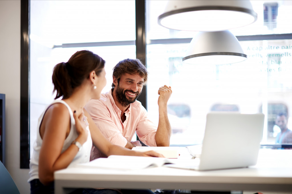 Young couple creating a budget for a business at a coffee shop using a laptop.