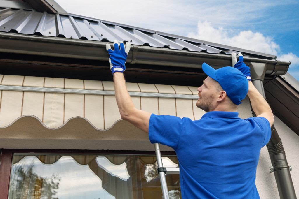 professional roofer in the ladder checking gutters