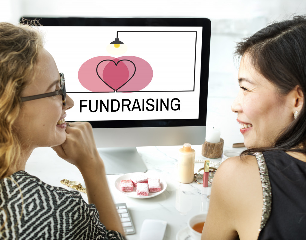 two women happily discussing a fundraising project in the computer screen