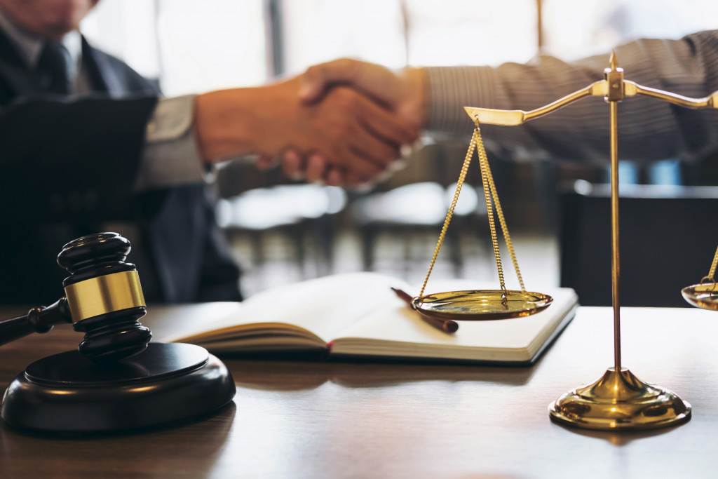 A gavel and a scale with two men shaking hands at the background