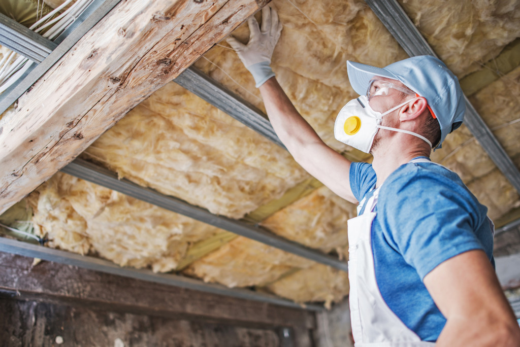 A man installing insulation on an old attic ceiling