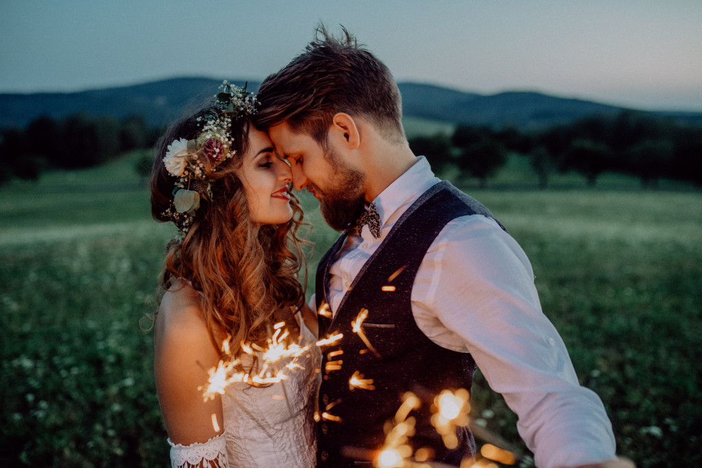 A bride and groom at a meadow with sparklers