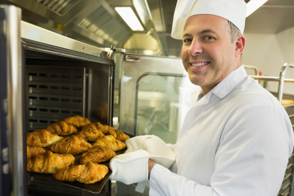 A baker taking croissants off an oven