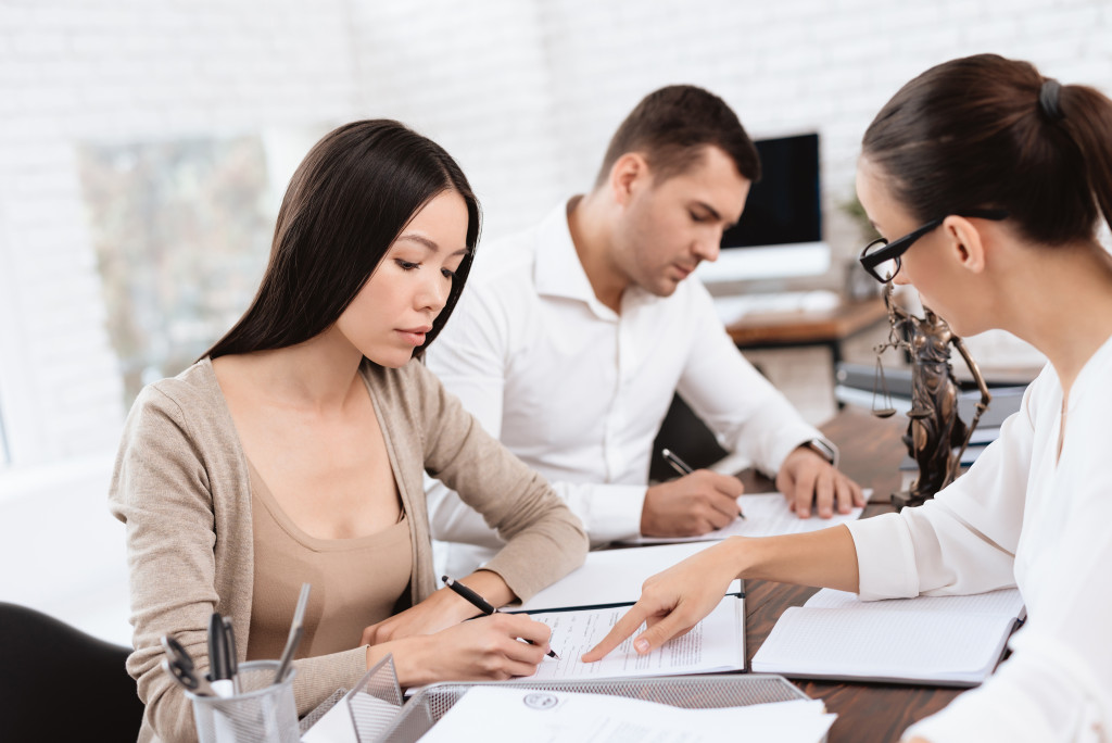 Couple signing divorce papers in front of a lawyer.