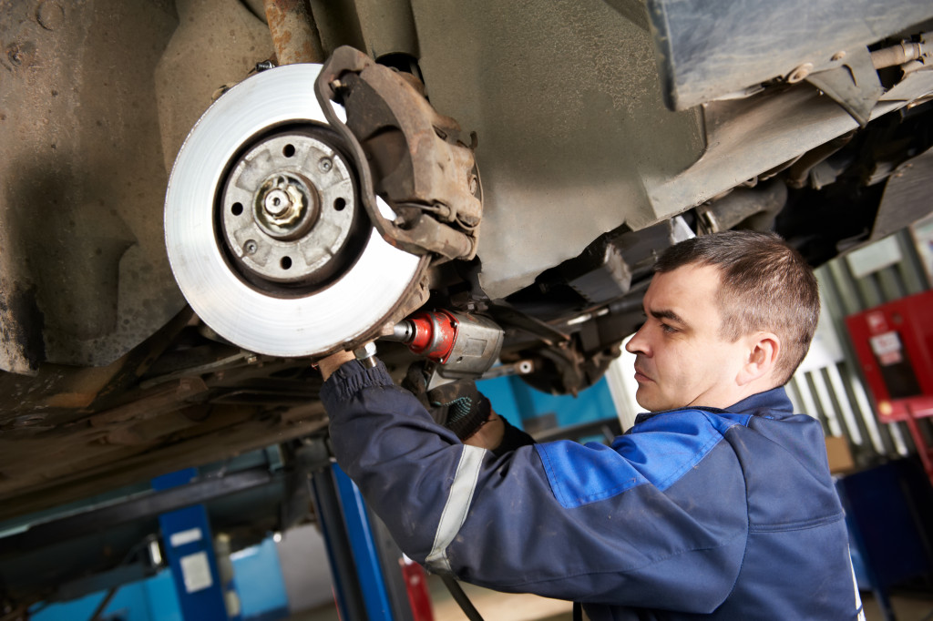 Auto mechanic working on the car suspension at an auto shop.